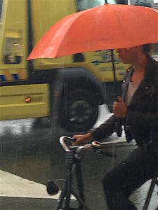 Amsterdammers ride in the rain--with an umbrella.